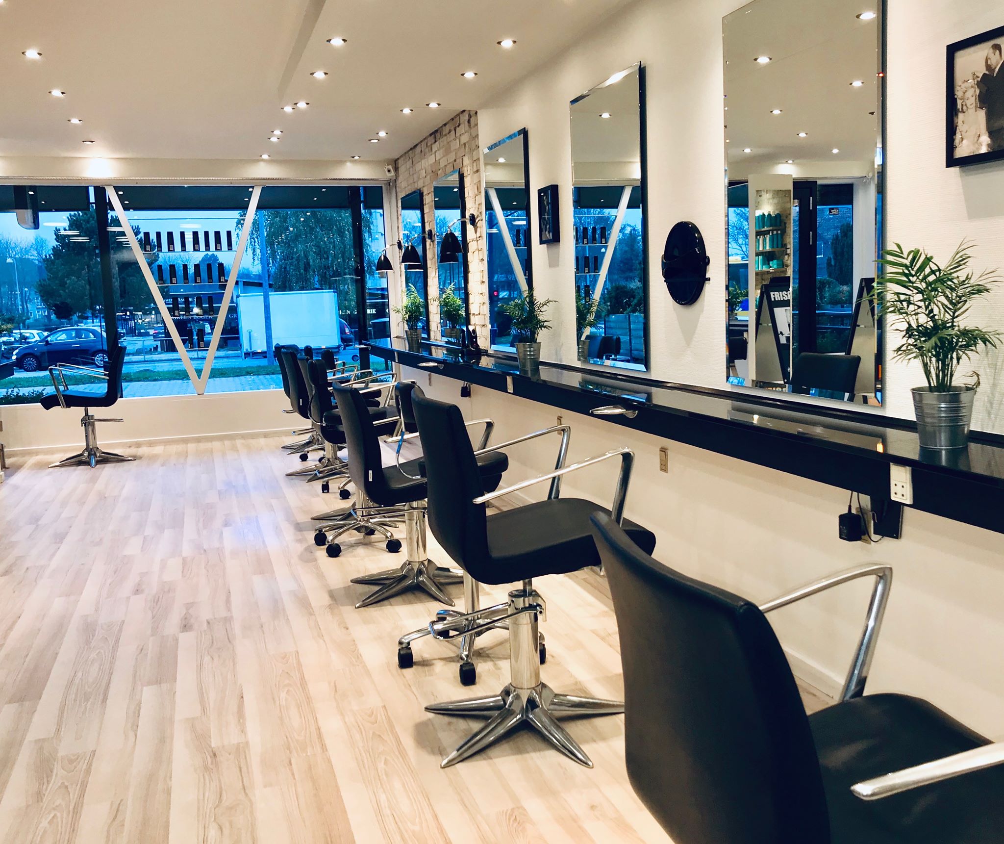 Frisør Vinholt - salonen med stylingstole langs den spejlbeklædte væg og store vinduer ud mod Sorgenfri Torv